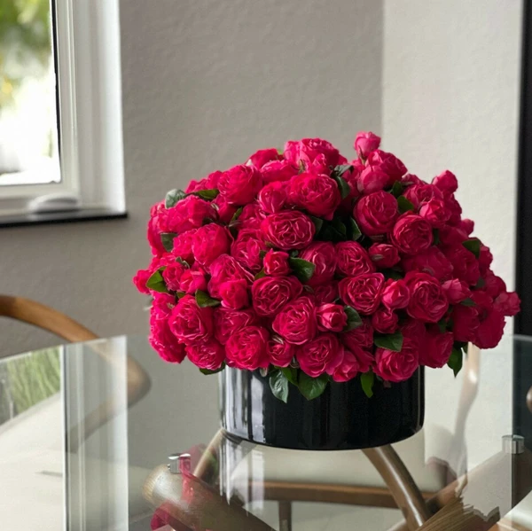 Rosas inglesas rosa-escuro em vaso de vidro preto.